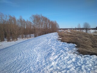Obraz premium hill slope covered with snow uneven surface with dry grass