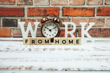 Work from Home alphabet letters with alarm clock on wooden background