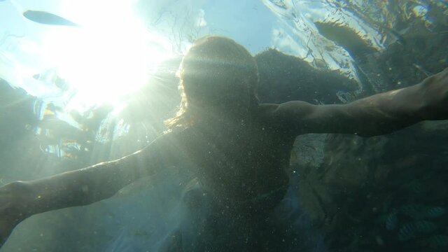 Woman in long dress swimming under water in slow motion
