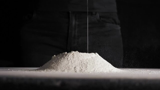 Chicken egg falls in slow motion into flour on black isolated background close up in 4K
