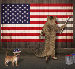 A beige cat patriot with a paintbrush draws the flag of usa on a wooden fence.