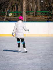Back view of a girl ice skating on the ice rink from Cismigiu park, in Bucharest