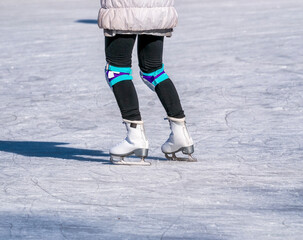 Legs of a woman with skates on ice. Ice skating recreational activity.