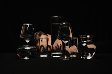 surreal portrait of a man looking through glasses of water