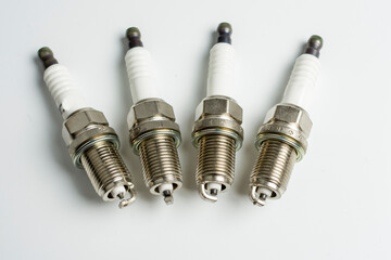 four spark plugs for a car on a white background