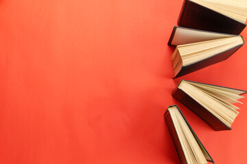 Group of  hardcover books on a red table.