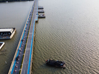 Obraz premium The view of the bridge with cars running and fishermen boats parked at sea, Transportation in Thailand.