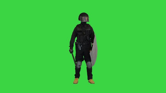 Riot police man with tactical baton and a shield standing and touching his face on a Green Screen, Chroma Key.