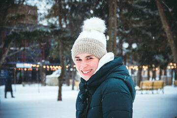 Young girl with blue eyes smiling on the background of snowfall and lanterns in the park on a winter day