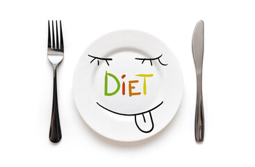 A white plate on which the word Diet is written standing on a cotton tablecloth and funny face is licked with hunger.The concept of a balanced diet, ration and medical fasting. Background, copy space.