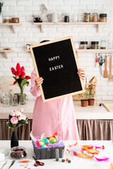 Naklejka na ściany i meble woman in pink dress holding black letter board with words Happy Easter