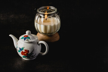 Teapot and glass jar with dark tone scented candles