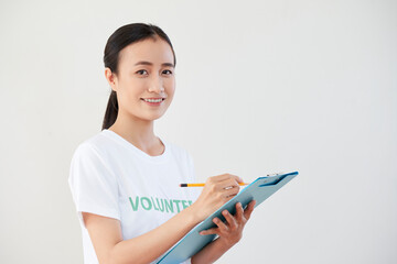 Pretty young Asian woman filling document for volunteer organization she is working for