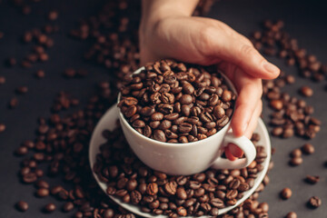 a cup with coffee beans stands on a saucer on a gray background close-up