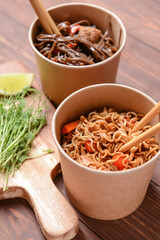 Bowls with tasty noodles on wooden background