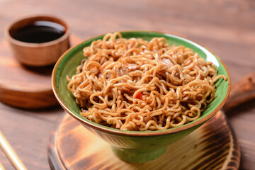 Bowl with tasty noodles and meat on wooden background