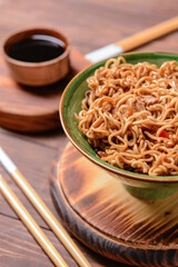 Bowl with tasty noodles and meat on wooden background