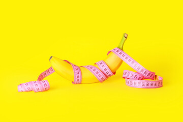 Ripe banana and measuring tape on color background. Weight loss concept