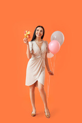 Beautiful woman with gift and balloons on color background. International Women's Day celebration