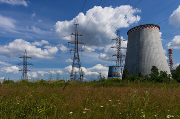 Thermal power plant with high-voltage transmission lines on the background of a summer meadow and blue sky