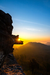 Vertical The morning sun shines through the rock on a high cliff.