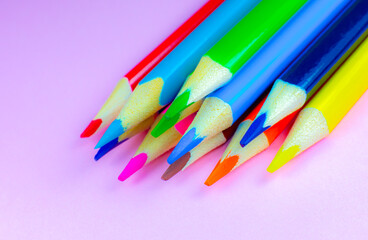 Color pencils lying on pink background. Close up. Back to school concept. Colorful art studying and painting process. Drawing with pencils. Copy space place for postcard wish.
