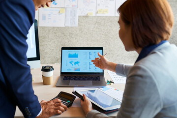 Business people discussing diagram on laptop screen at meeting and anazyling sales and company profit