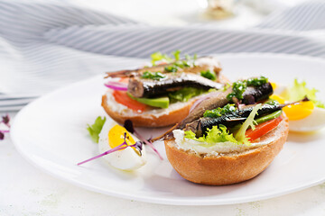 Sandwich - smorrebrod with sprats, avocado, tomatoes, eggs and cream cheese on white plate. Danish cuisine.  Eco friendly concept.