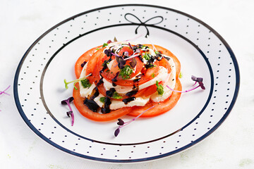 Caprese salad. Mozzarella cheese, tomatoes and basil pesto on plate.  Eco friendly concept.