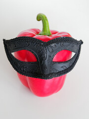 Red pepper in a black carnival mask on a white background humorous photo