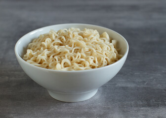 Pre-cooked ramen noodles in an white bowl on a gray background