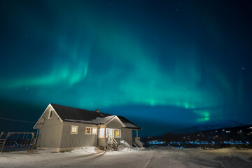 Aurora borealis over a house in the mountains.