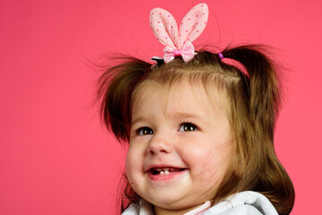 Cute smiling Easter bunny baby toddler with ears closeup and isolated on pink background.
