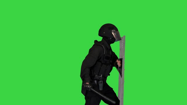 Policeman with full equipment for anti-riot running into the frame and rising the shield on a Green Screen, Chroma Key.
