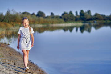 A teenage girl on nature walks along the river bank on a sunny day.