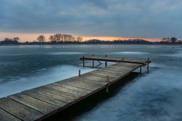 Wooden pier and a frozen lake, view after sunset, Stankow, Lubelskie, Poland