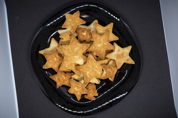 A scary homemade cookie in the shape of stars lies on a black plate. Close-up
