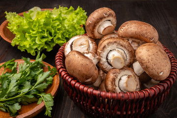 mushrooms in a basket with lettuce and herbs on a dark wooden background