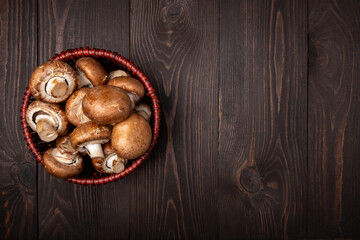 Obraz premium mushrooms in a basket on a dark wooden background top view with copy space