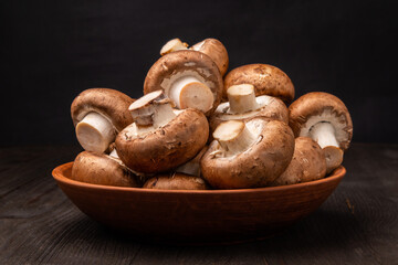 mushrooms in a clay bowl on a dark wooden table
