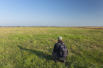 Fototapeta na wymiar A traveler with a backpack will crouch on the meadow, Srebrzyszcze, Poland