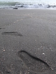 big footprints are on the black sand beach design for trace concept