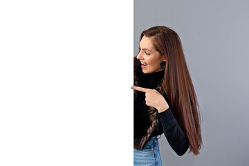 emotional young teenager woman showing blank signboard with copy space, isolated on gray