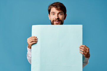 bearded man holding a banner advertising blue background in front of him