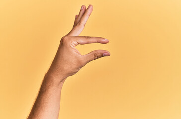 Arm and hand of caucasian man over yellow isolated background picking and taking invisible thing,...