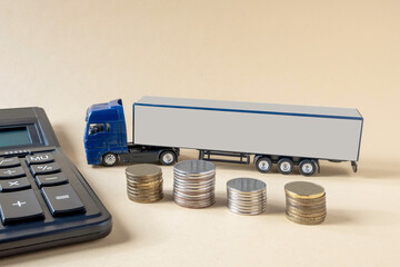 Calculator, mock-up of tractor-trailer, coins placed on light background. Concept. Tariffs, calculation, freight transport costs by truck.