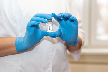 Obraz premium The hands of a doctor or nurse are holding a bottle of coronavirus vaccine.