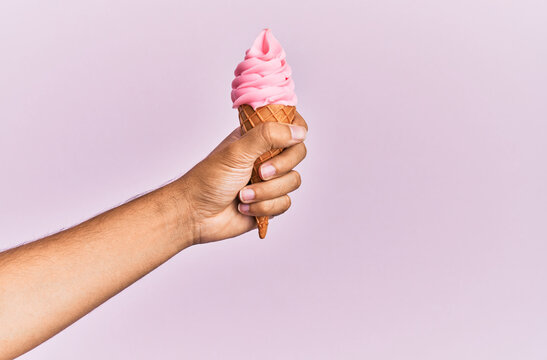 Hand Of Hispanic Man Holding Ice Cream Over Isolated Pink Background.