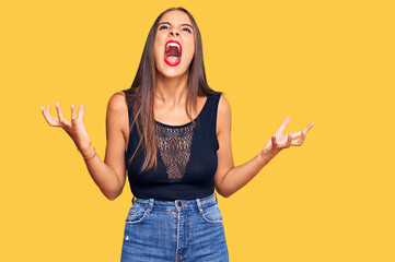 Young hispanic woman wearing casual clothes crazy and mad shouting and yelling with aggressive expression and arms raised. frustration concept.