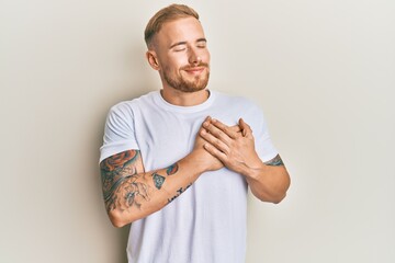 Young caucasian man wearing casual white tshirt smiling with hands on chest, eyes closed with grateful gesture on face. health concept.